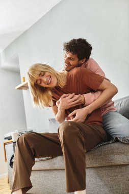 İki neşeli adam rahat bir yaşam alanında kucaklaşır. Sevgi ve mutluluk yayarlar..