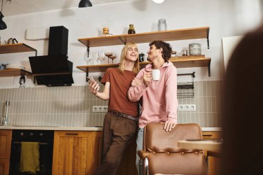 İki adam şık mutfaklarında gülüyor, aşkı ve birlikteliği kutluyorlar..