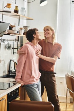 Neşeli bir mutfakta birbirine gülümseyen iki adam birlikte aşk ve mutluluğu kutluyorlar..