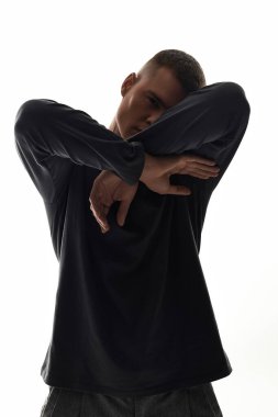 A young man in a stylish outfit poses against a light backdrop, expressing emotion and art. clipart