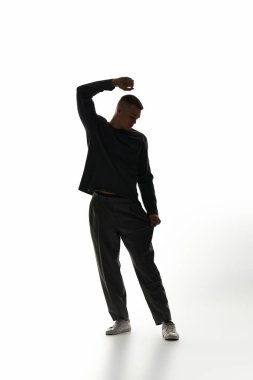 Genç ve yakışıklı bir adam, yaratıcı bir poz verirken, çarpıcı bir siluet sergiliyor..