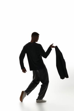 Kendine güvenen genç bir adam parlak bir arkaplana karşı zarif bir ceketle poz verir..