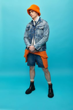 Genç bir adam kendinden emin bir şekilde koyu turuncu aksanlı kot ceket giyiyor..