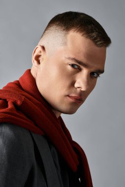 Genç, yakışıklı bir adam kendine güvenerek poz verir, şık bir elbise ve canlı bir eşarp giyer..