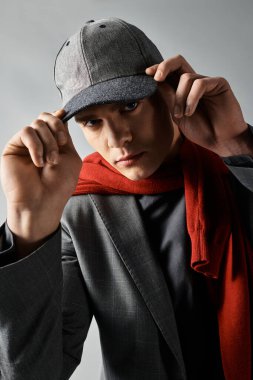 Şapkalı ve atkılı havalı genç adam moda anlayışını şehir atmosferinde sergiliyor..