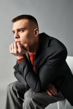 Yakışıklı genç bir adam, parlak bir arka planda derin düşüncelere dalmış elinde dinleniyor..