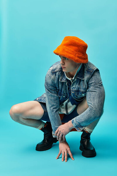 A young man confidently poses in a trendy outfit against a vibrant backdrop.