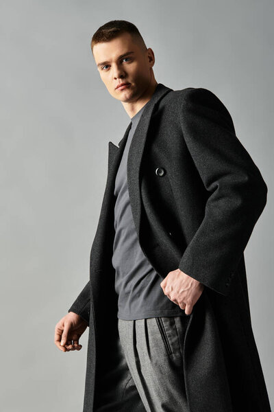 A young man in a modern outfit poses stylishly against a minimalist background.