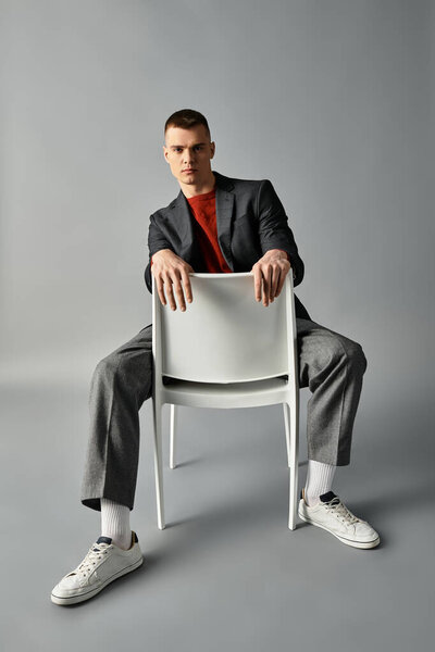 Молодой человек в пиджаке и кроссовках привлекает зрителя расслабленной, но уверенной позой..