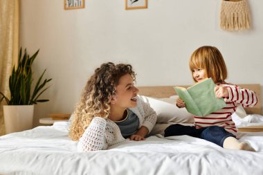 Neşeli bir anne ve kızı, sıcak yatak odalarında birlikte kitap okurken özel bir anı paylaşıyorlar..
