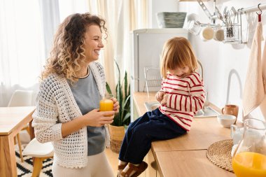 Kıvırcık saçlı anne, kızıyla sıcak mutfaklarında eğleniyor..