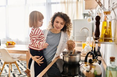 Anne ve kızı, evde yemek hazırlarken ve aile hayatını kucaklarken keyifli bir anı paylaşıyorlar..