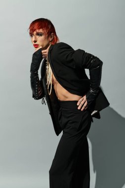 Kızıl saçlı kendine güvenen genç adam cesur, dramatik moda seçimleri sergiliyor..