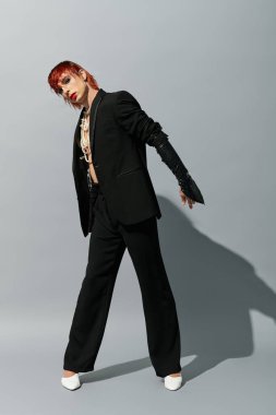 Genç bir adam şık bir kıyafetle stüdyoda yaratıcı bir şekilde poz veriyor..