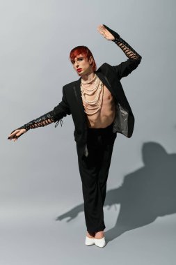 Genç bir adam dikkat çekici bir duruş sergiliyor, benzersiz moda seçimleri ve ifadeleri sergiliyor..