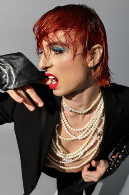 Canlı kızıl saçlı ve dinamik kıyafetli genç bir adam görsel olarak çarpıcı bir şekilde poz veriyor..