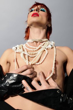 A unique young man showcases an artistic style with layered pearl necklaces and bold makeup. clipart