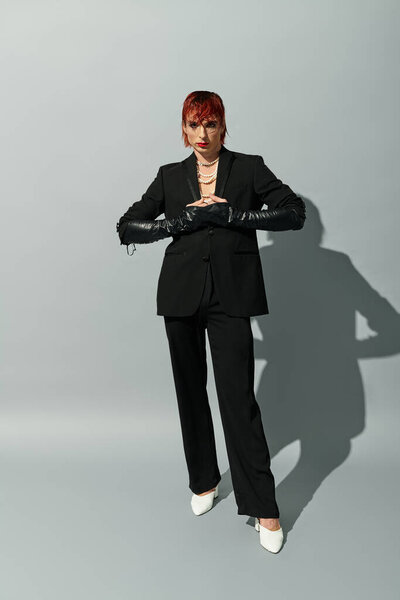 A stylish young man stands confidently in a sleek suit, highlighting his distinctive fashion sense.