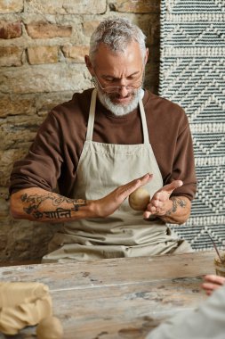 Olgun bir adam çömlek kursunda kil şekillendirmekten hoşlanır.