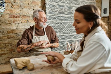 Bir çift çömlekçilik kursundan zevk alıyor, birlikte ustalıkla kil şekillendiriyorlar..