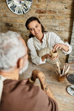 Olgun çift, yaratıcılıkla dolu kırsal bir çömlek atölyesinde kil şekillendirerek kaliteli zaman geçirmeyi sever..
