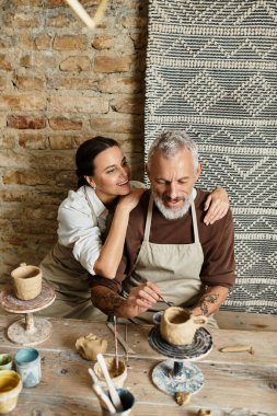 Bir çift çömlekçilik dersinde kil şekillendirmekten zevk alır..