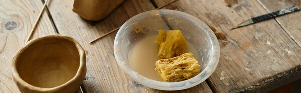 shaping clay near tools, sponges and finished pottery in an inviting studio space, banner