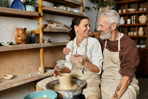 A mature couple enjoys shaping clay and laughing while attending a pottery class.