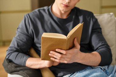 Yakışıklı genç adam evinde, modern dairesinde bir kitapla rahatlıyor, sükuneti kucaklıyor..