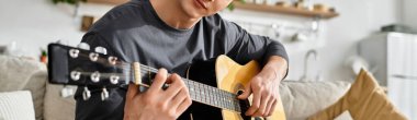 Genç bir adam rahat dairesinde akustik gitar çalıyor, öğleden sonranın keyfini çıkarıyor, afiş.