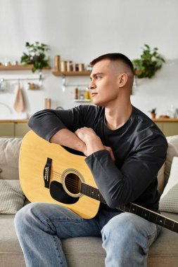 Genç bir adam gitarını modern bir dairede, rahat ve evinde çalmaktan hoşlanır..
