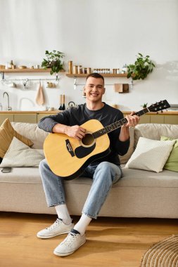 Yakışıklı genç adam modern dairesinde dinlenirken gitar çalıyor..