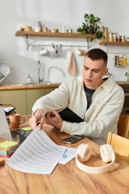 Young man works freelance in his stylish home office, focused on important documents. clipart