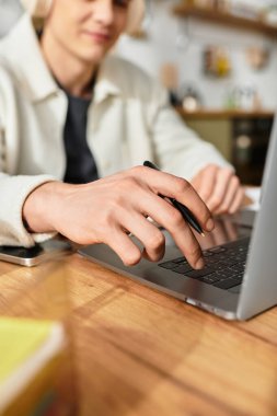 A young man in casual clothes focuses on his laptop, engaged in remote work at home. clipart