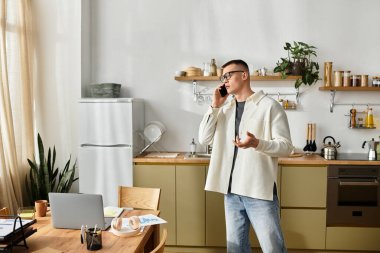 Genç bir adam, çağdaş dairesinde serbest görevleri dengelemek için telefonla konuşuyor..