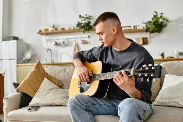 Молодой человек в повседневной одежде играет на гитаре дома, окруженный простым, но стильным декором.
