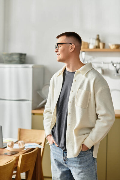 A young man dressed casually works on his laptop in a stylish home environment.
