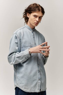 Kendine güveni tam genç bir adam, minimalist bir alanda kişisel tarzını ifade eden, modern bir kot giysisi sergiliyor..