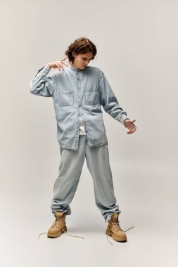 Yakışıklı genç bir adam şık kotunu sergiliyor özgüven ve hünerle sade bir arka planda.