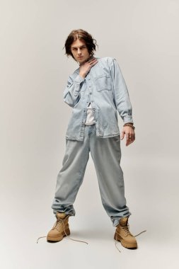 Yakışıklı genç bir adam kot elbise giyer, kendine güvenerek şık bir şekilde poz verir..