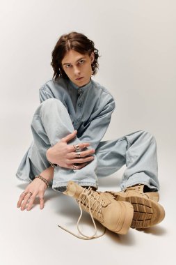 Kot giymiş genç, yakışıklı bir adam şık ayakkabılarını çizerken zarif poz veriyor..