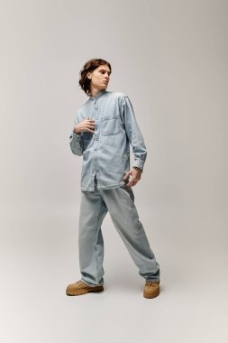 Yakışıklı genç adam stili ile duruyor, minimalist bir ortamda modern moda sergiliyor..