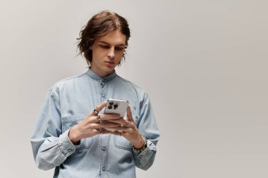 Kot gömlekli yakışıklı adam akıllı telefonuna odaklanmış, tarz ve kendine güven yayıyor..
