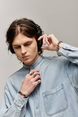 Rahat bir ifadeyle yakışıklı genç bir adam minimalist bir stüdyoda müzik dinliyor..