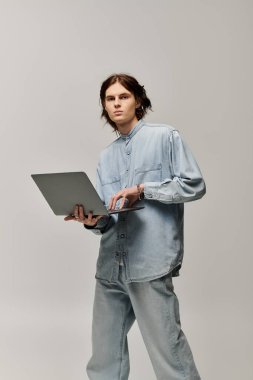 Kot giymiş yakışıklı genç adam, çağdaş bir stüdyo ortamında dizüstü bilgisayarına odaklanıyor..