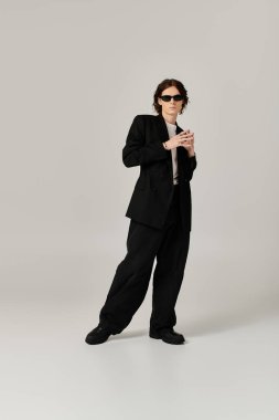 Siyah takım elbiseli, güneş gözlüklü yakışıklı genç adam sofistike bir havayı tasvir ediyor..