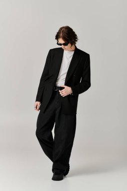 Özel dikim siyah takım elbiseli yakışıklı genç bir adam şık bir stüdyoda kendine güven ve tarz yayar..