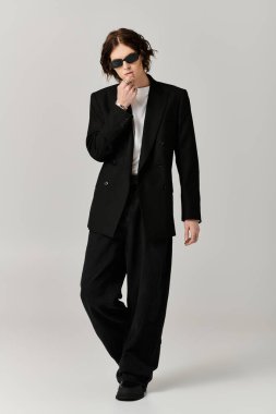 Yakışıklı genç bir adam modaya uygun siyah giysiler içinde şık tavırlarını sergiliyor..