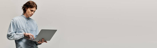 Красивый молодой человек со стильной одеждой фокусируется на своем ноутбуке во время мозгового штурма идей.