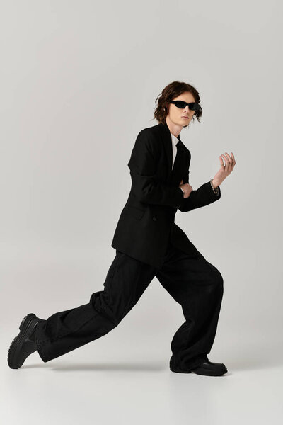 Handsome young man dressed in fashionable attire showcases confident movement indoors.